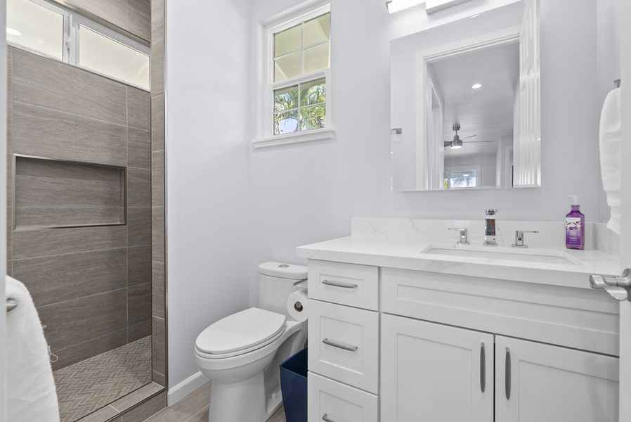 Full bath with walk-in shower, stone tile walls, and spacious vanity—just steps from guest areas.