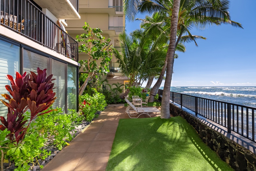 Charming outdoor space with seating, nestled by the ocean and surrounded by tropical foliage—ideal for relaxation.