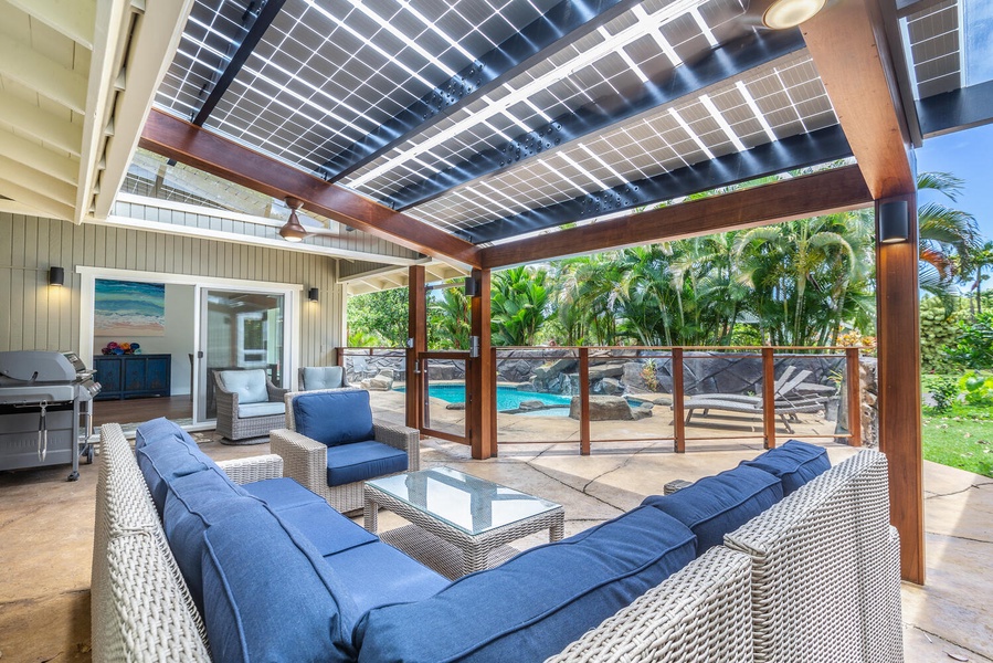 Covered lanai at Lani Oasis with shaded lounge seating beside the pool, ideal for outdoor gatherings.