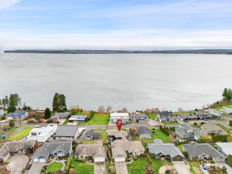 Aerial view of waterfront neighborhood with homes nestled along the shoreline, offering peaceful residential setting near the lake.