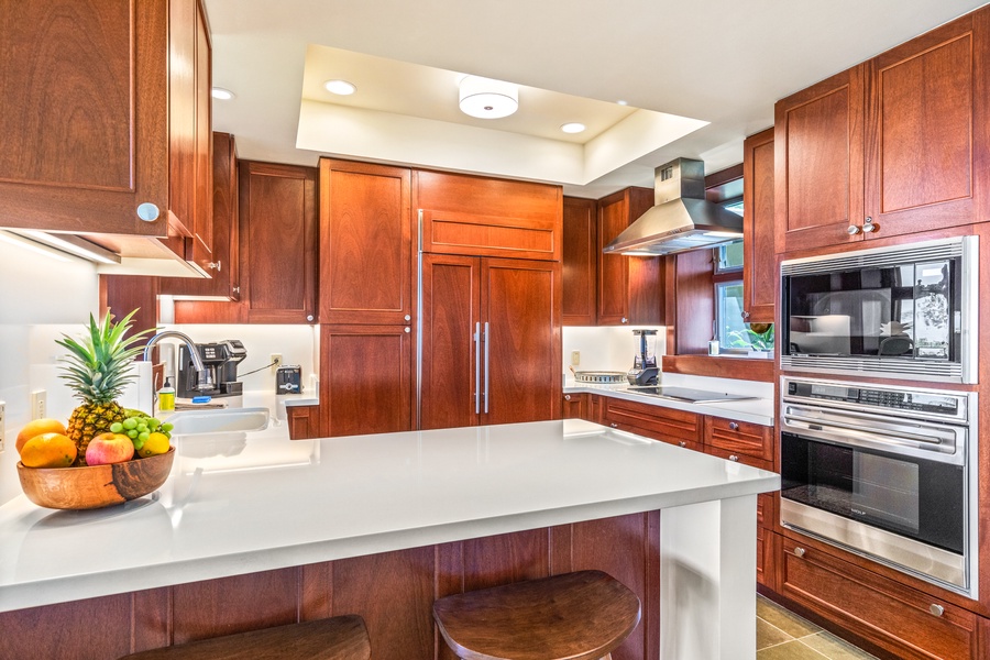 Gleaming modern kitchen with bar seating and top tier appliances.