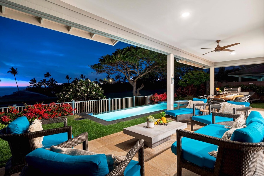 Nighttime view of a poolside lanai with vibrant seating and soft lighting, ideal for evening relaxation.