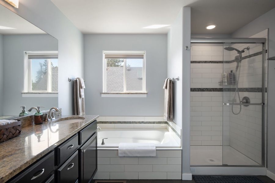 Refresh in the spacious ensuite bathroom featuring dual vanities, a soaking tub, and walk-in glass shower.