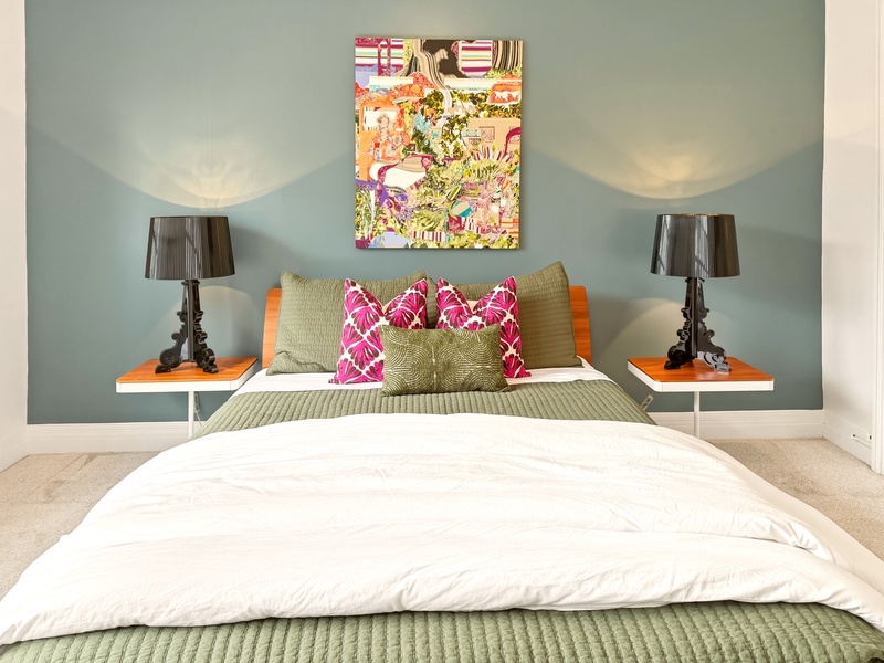 Slip into crisp white linens and sink into your colorful retreat, where vibrant art and cozy textures create the perfect restful escape.