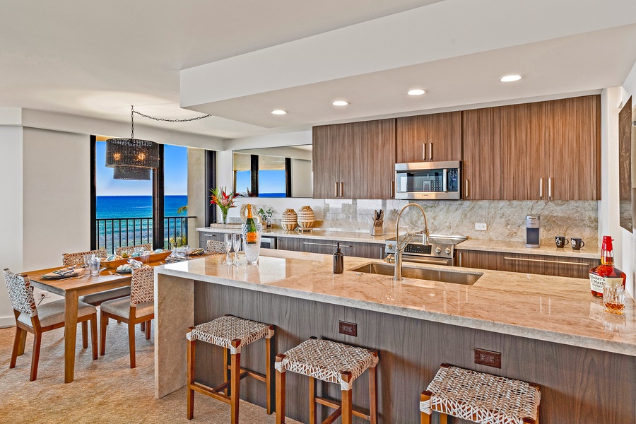 This modern kitchen features a large island with seating, stainless steel appliances, and stunning ocean views.