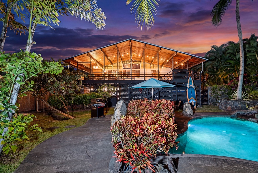 Offering dramatic sunset views and illuminated architecture amid lush palms and a sparkling pool.