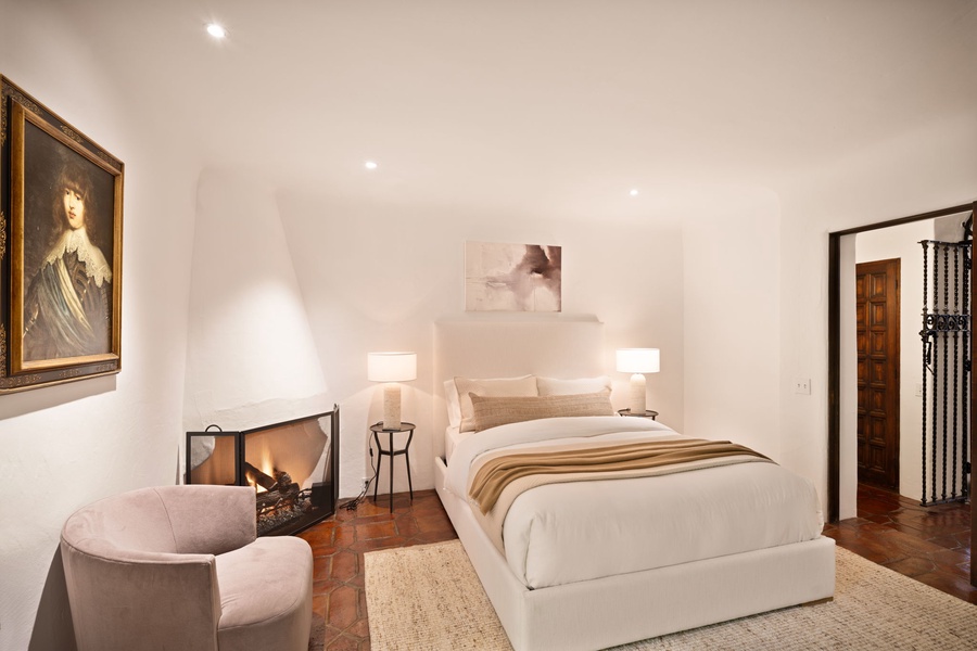 Unwind in this elegant bedroom where classical art meets modern comfort. Your cozy fireplace and plush seating create the perfect romantic retreat.