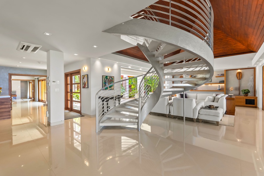 Step into a beautifully designed open-concept space where modern elegance meets warm island-inspired touches. The dramatic spiral staircase and polished floors reflect natural light, creating an airy, welcoming vibe.