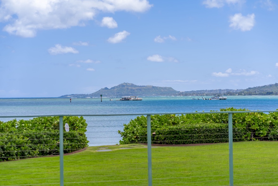 Stunning oceanfront property with panoramic views across turquoise waters to distant volcanic peaks. The lush lawn and privacy hedges create a perfect island retreat setting.