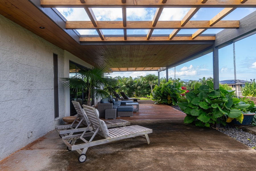 Relax under this stylish pergola, surrounded by lush greenery and comfortable lounge seating for a peaceful outdoor retreat.