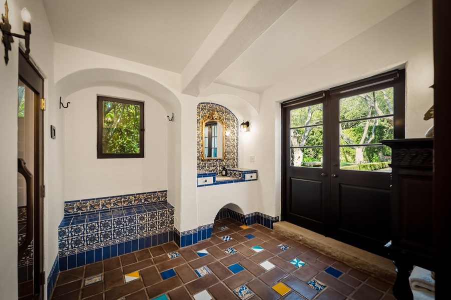 Immerse yourself in this stunning Spanish-style bathroom with hand-painted tiles, vaulted ceilings, and peaceful garden views.