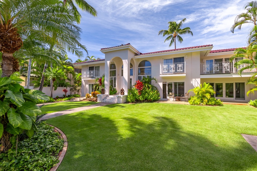 Impressive front view of the villa with a grand entrance, manicured lawn, and tropical landscaping.