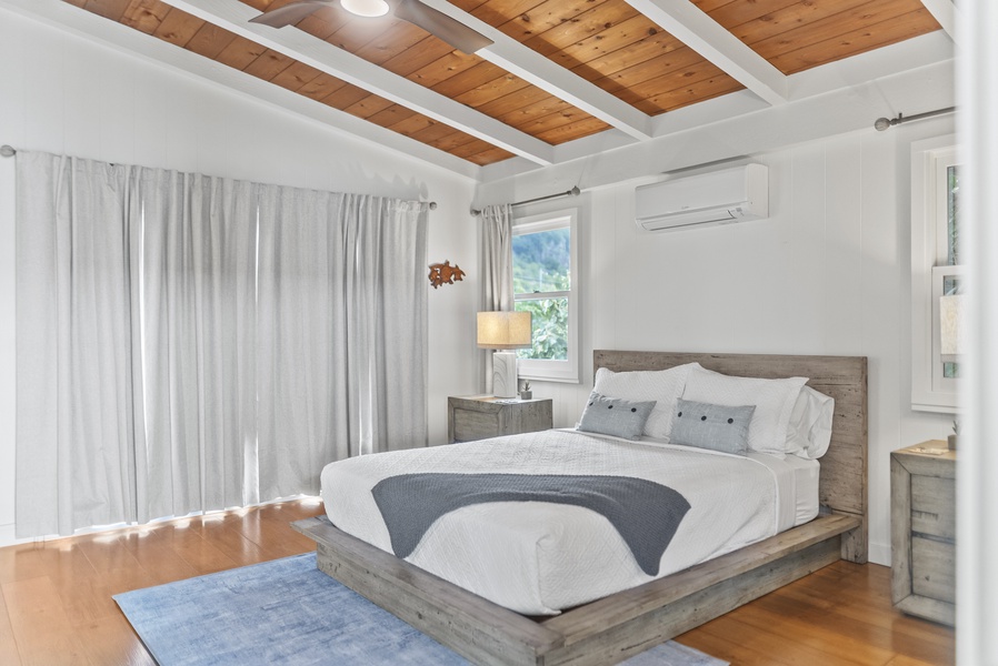 Serene primary bedroom with a plush queen bed, vaulted ceilings, and soft natural light for restful North Shore mornings.