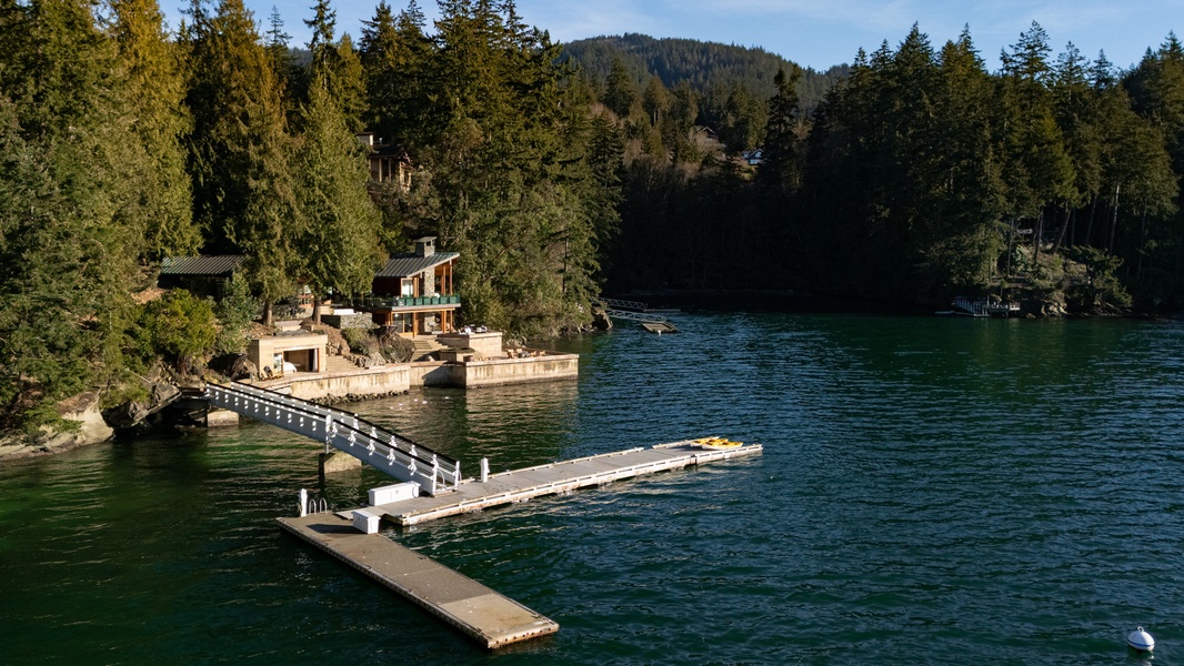 A private waterfront property with dock and kayak access, nestled among forested mountains beside pristine lake waters.