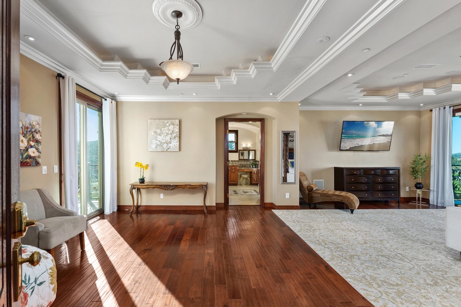 Dark hardwood floors extend beneath a tray ceiling, offering an elegant backdrop for work, relaxation, or entertaining.