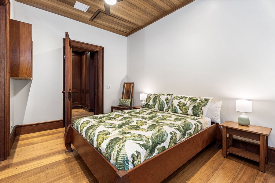 Unwind in your serene bedroom with tropical-print bedding, rich wood details, and warm lighting for peaceful nights.