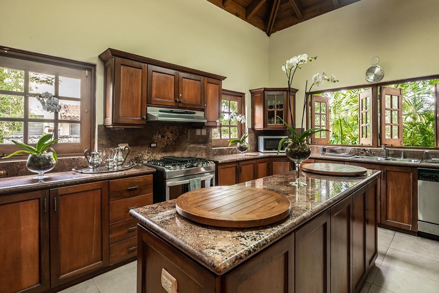 The kitchen is surrounded by lush views, featuring a wooden cabinetry and countertops.
