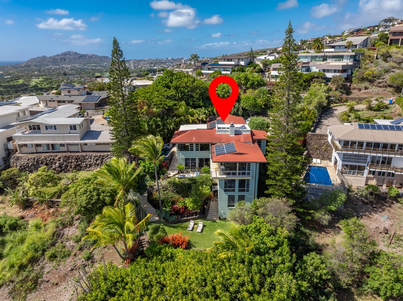 Pin-drop aerial highlights the home’s elevated setting and lush privacy above Honolulu.