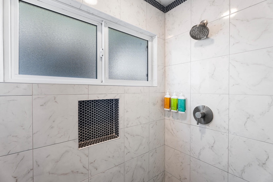 Bright, modern walk-in shower with rainfall head and natural light.