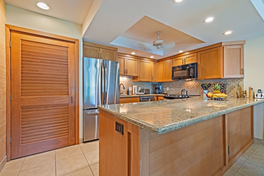 The modern kitchen at Kahana Sunset B4B boasts granite countertops, stainless steel appliances, and ample storage for easy meal prep.
