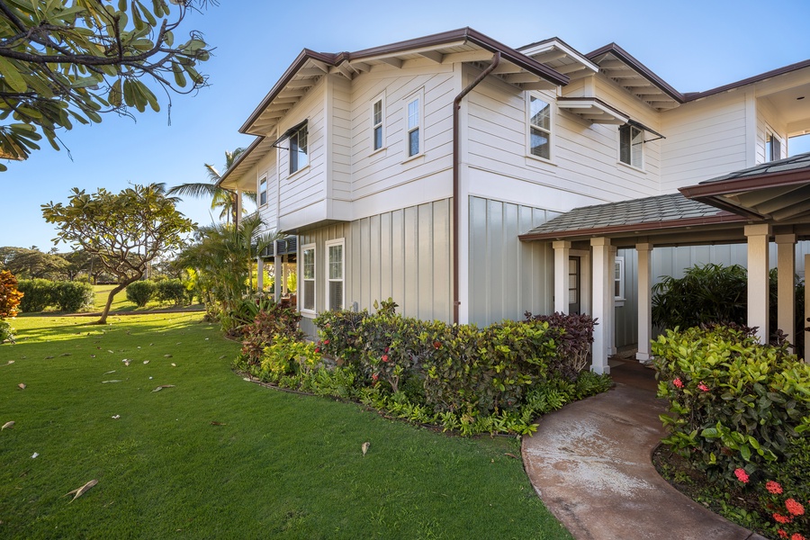 Elegant two-story property featuring pristine white exterior, mature tropical landscaping, and expansive green lawn surrounding the building.