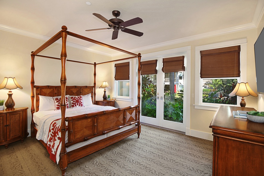 The primary bedroom at Unit B111 features a four-poster bed, direct access to a lanai, and a luxurious en suite bathroom with a deep soaking tub and dual vanities.