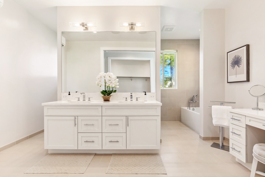 Primary bathroom featuring dual sinks, an elegant design, and a separate vanity area.