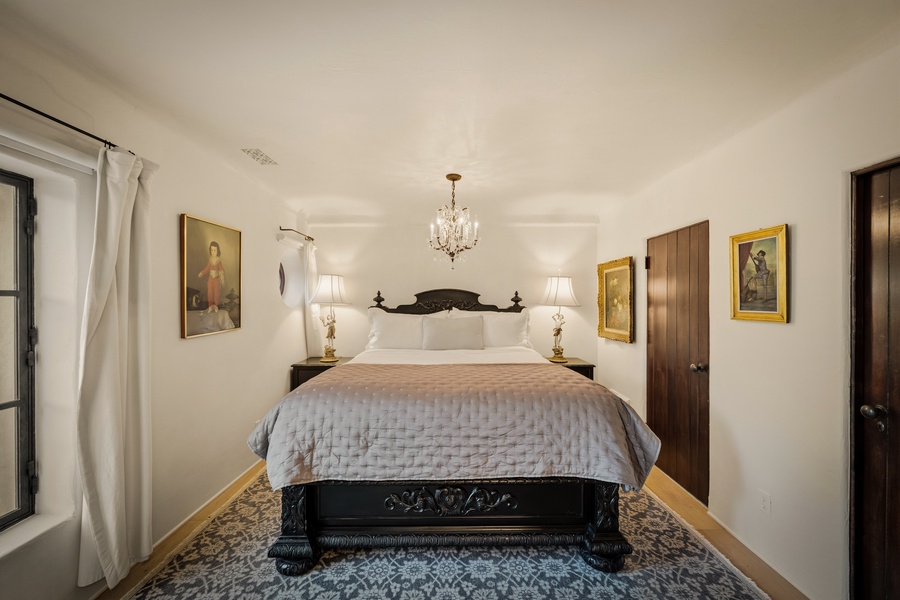 Drift off in your elegant bedroom with ornate headboard, crystal chandelier, and vintage artwork creating timeless charm.