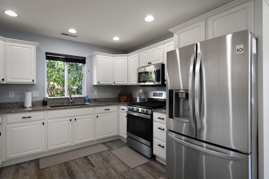 Cook with ease in the bright chef-ready kitchen featuring stainless steel appliances and expansive countertops throughout.