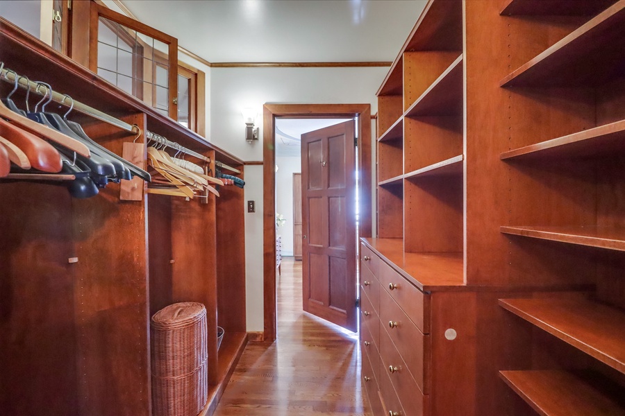 Guest room 1's walk-through closet with plenty of shelving and storage options, leads to the primary bedroom.