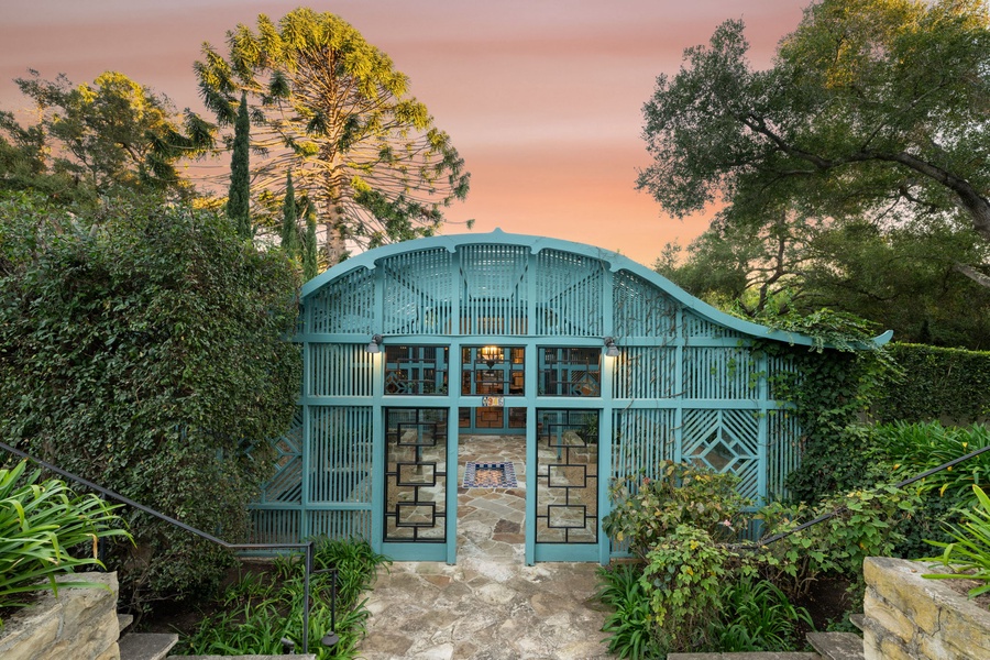 Stunning sunset illuminates this distinctive turquoise building surrounded by lush tropical landscaping and mature trees.