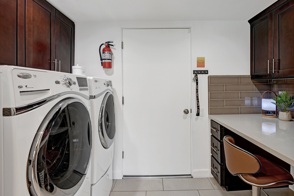 Classic cottage laundry room features a white and gray granite countertop  positioned over a sil…